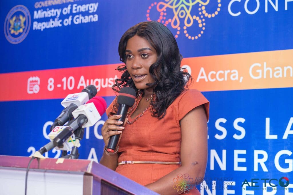 A woman speaks into a microphone in front of the conference backdrop at the press launch of the first Africa Energy Technology Conference, Alisa Hotel, Accra, June 2023